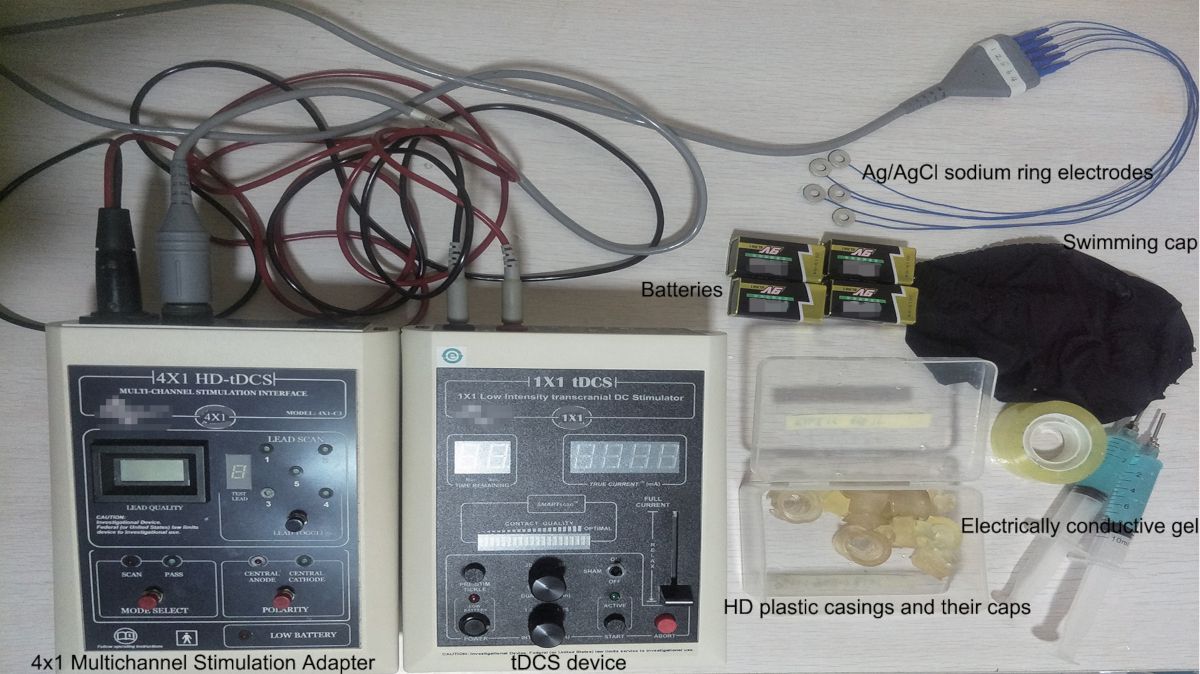 Transcranial DC stimulation setup with multichannel adapter, electrodes, batteries, and conductive gel.